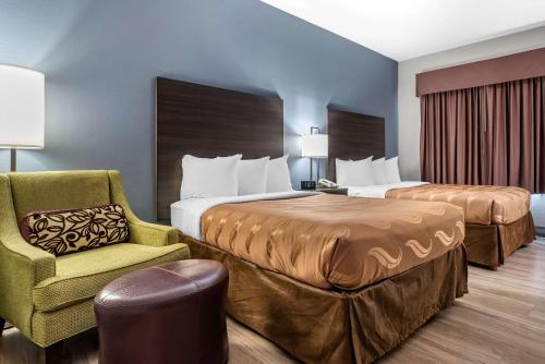 a hotel room with two beds and a chair at Quality Inn & Suites Demopolis in Demopolis
