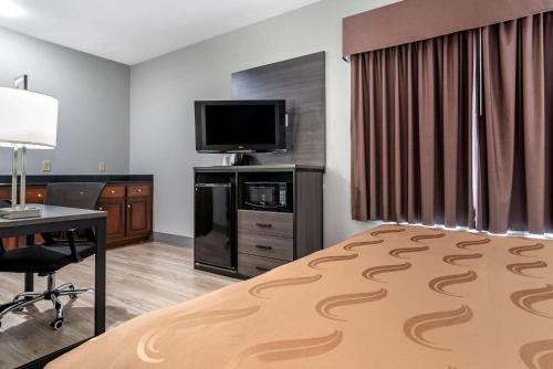 a hotel room with a bed and a desk and a television at Quality Inn & Suites Demopolis in Demopolis