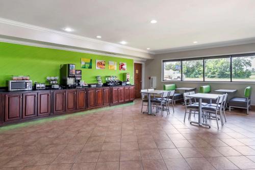 a restaurant with tables and chairs and a green wall at Quality Inn & Suites Demopolis in Demopolis
