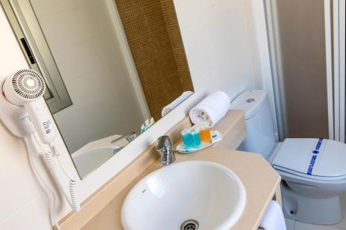 a bathroom with a sink and a mirror and a toilet at Flats Friends Atlantida in Benidorm