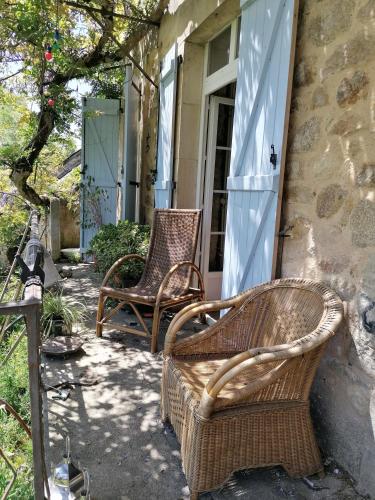 two wicker chairs sitting on the porch of a house at Le Temps Serein in Vabre-Tizac