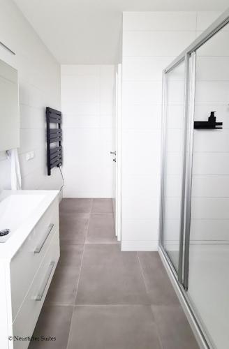 a white bathroom with a shower and a glass door at Friendship Suite in Mörbisch am See