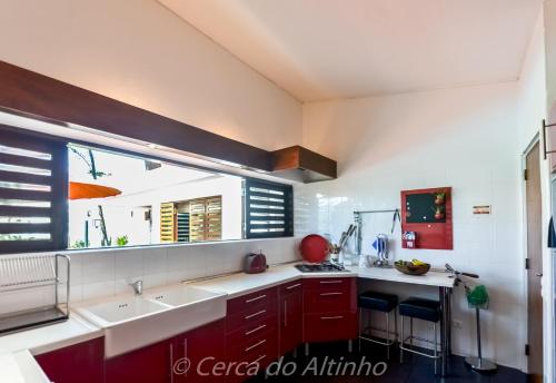 a kitchen with red cabinets and a large window at Cerca do Altinho in Vila Nova de Milfontes