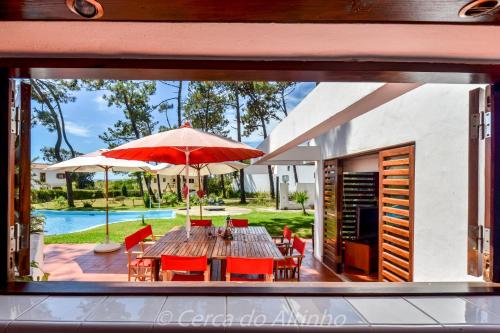 a dining room with a table and chairs and an umbrella at Cerca do Altinho in Vila Nova de Milfontes