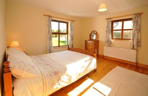 a bedroom with a bed and a dresser and two windows at BunkHouse - Letterfrack Farm in Letterfrack