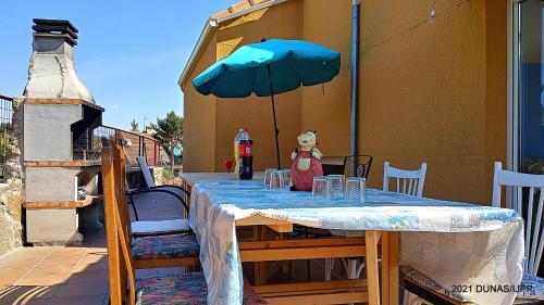a table with a teddy bear sitting under an umbrella at Casa Rural Dunas in Santa María de la Alameda
