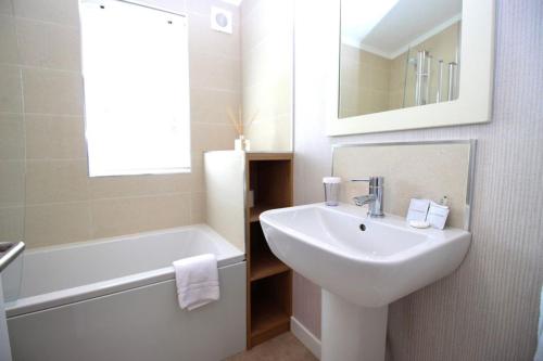 a white bathroom with a sink and a tub and a mirror at Hollicarrs - Bumblebee Lodge in York