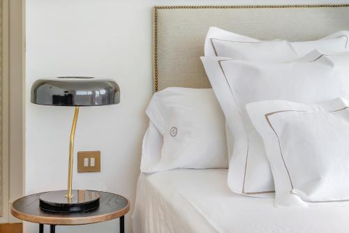 a bed with white pillows and a table with a lamp at Hoposa Daina- Adults Only in Port de Pollensa