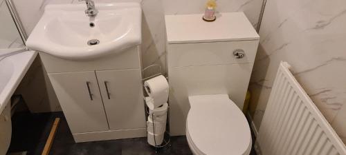 Baño blanco con lavabo y aseo en Espedair Apartment, en Paisley