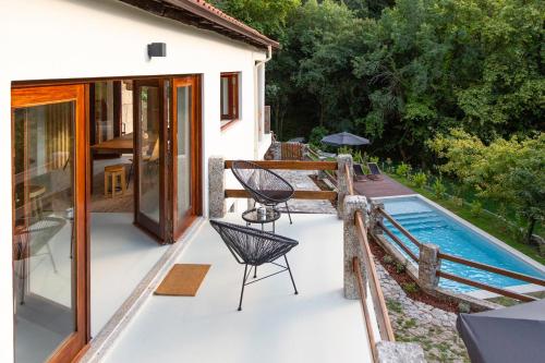 a patio with a pool and a chair next to a house at Casa Soenga in Vieira do Minho