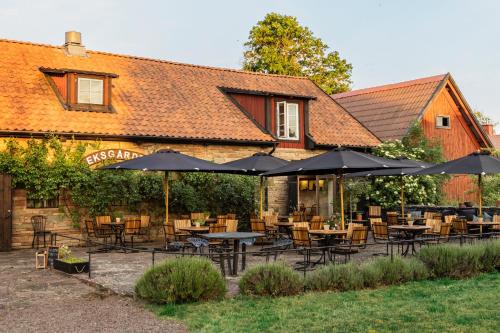 un restaurante con mesas, sillas y sombrillas en Eksgården, en Färjestaden