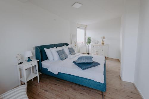 um quarto com uma cama azul e branca e uma mesa em Stijlvol appartement op strand Makkum em Makkum
