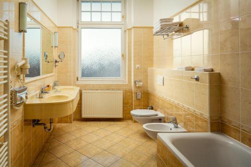 a bathroom with two sinks and a tub and a toilet at Spa Hotel Imperial in Karlovy Vary