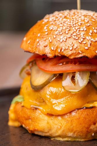 a hamburger with cheese and tomatoes and onions at Pensiunea Iristar in Fălticeni