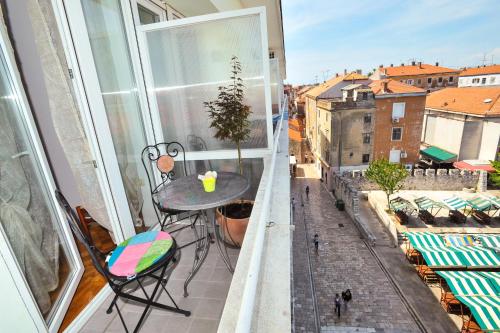 a table and chairs on a balcony with a window at Zadar Old Town Apartments II in Zadar