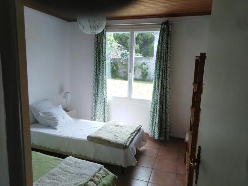 - une chambre avec 2 lits et une fenêtre dans l'établissement Maison oléronaise avec la plage à pied et la piste cyclable au bout du jardin, à Dolus-d'Oléron