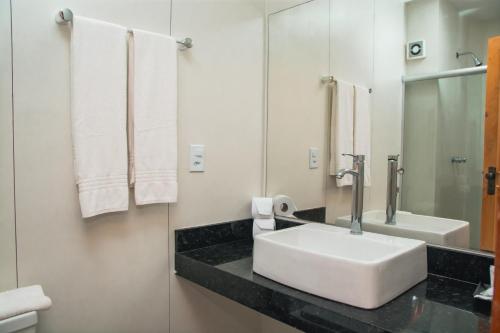 W łazience znajduje się biała umywalka i lustro. w obiekcie Cahy Praia Hotel w mieście Prado