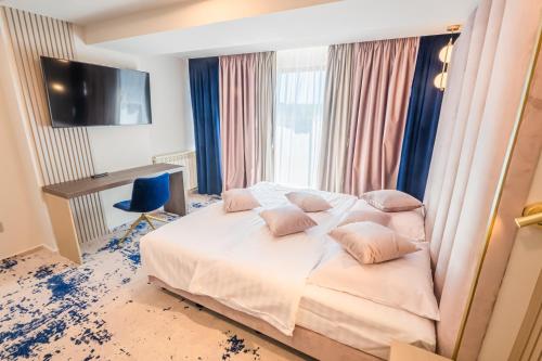 a bedroom with a bed with pink pillows and a desk at Pensiunea Iristar in Fălticeni