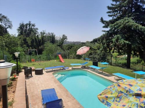 a swimming pool with blue chairs and an umbrella at Il Mandorlo in Ficulle