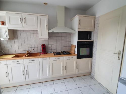 une cuisine avec des armoires blanches et un comptoir dans l'établissement VILLA MEDOC OCEAN 2, à Talais