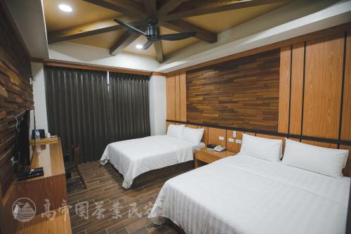 a hotel room with two beds and a flat screen tv at Gaodiyuan Tea B&B 高帝園茶業民宿 in Meishan