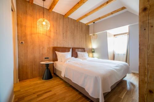 a bedroom with a white bed and a wooden wall at Ski Hotel in Žabljak