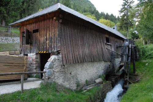 a wooden building with a waterfall in front of it at Alpenresort Belvedere in Molveno