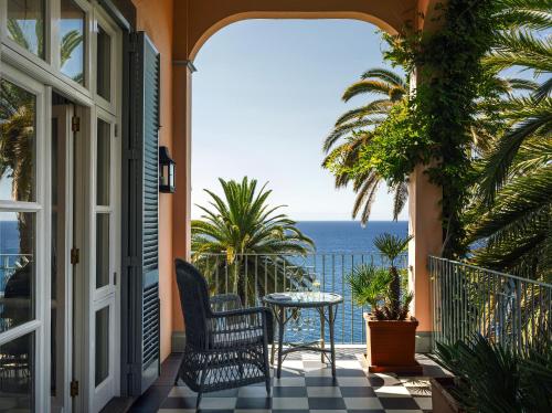 a balcony with a table and a view of the ocean at Reid's Palace, A Belmond Hotel, Madeira in Funchal