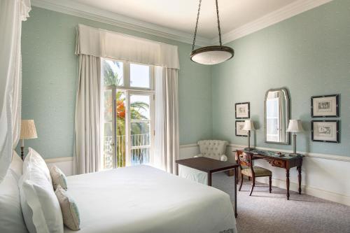 a bedroom with a bed and a window and a desk at Reid's Palace, A Belmond Hotel, Madeira in Funchal