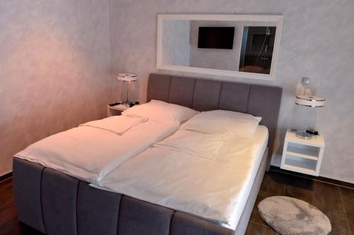 a bed in a room with two lamps and a mirror at Apartmani i Bungalovi TROJKA in Banja Luka