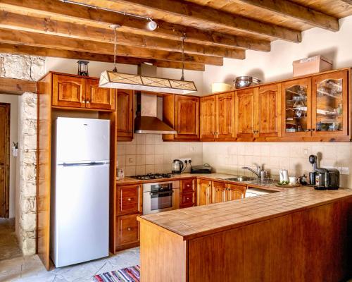 een keuken met houten kasten en een witte koelkast bij Listed Villa in Laneia in Lania