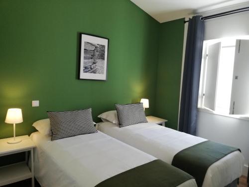 two beds in a room with green walls at Villa Graça -Hostels and Apartments in Santarém