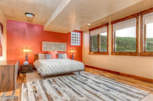 a bedroom with orange walls and a bed and windows at The Perch Park City - Magnificent 6 BR House With Views, Elevator, Game Room, Hot Tub in Park City