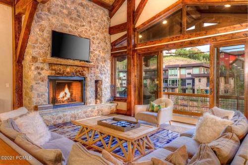 a living room with a fireplace and a stone wall at The Perch Park City - Magnificent 6 BR House With Views, Elevator, Game Room, Hot Tub in Park City