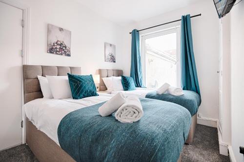 2 camas individuales en un dormitorio con cortinas azules en Chesshyre Accommodation - TV in Every Bedroom!, en Swansea