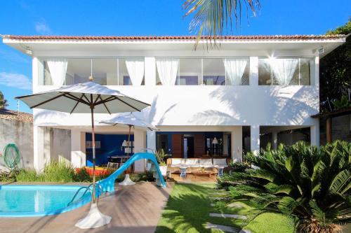 a white house with a slide and a swimming pool at Casa pé na areia na Praia de Genipabu by Carpediem in Extremóz