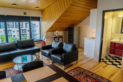 a living room with black leather furniture and a kitchen at Hverfisgata Apartment in Reykjavík