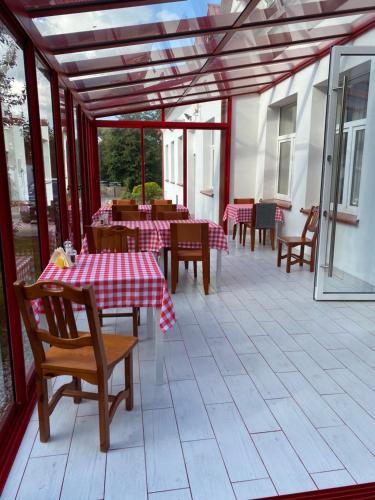 un patio con tavoli e sedie e panna da tavola rossa e bianca di Gościnec pod lipami a Kruszyniany