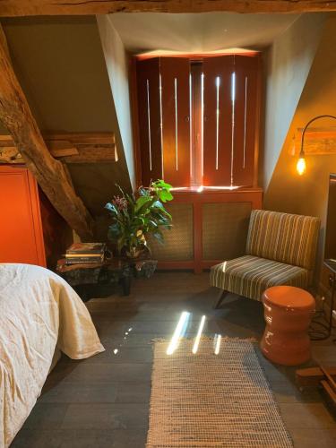 a bedroom with a bed and a chair and a window at Maison Fred Luxury Suites in Bruges