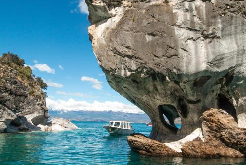 a boat in the water next to a rock formation at Casa Cerro Castillo in Villa Cerro Castillo
