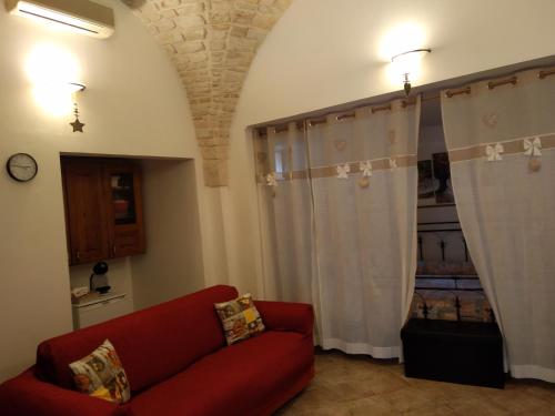 a living room with a red couch and curtains at Soggiornare In Centro in Alberobello