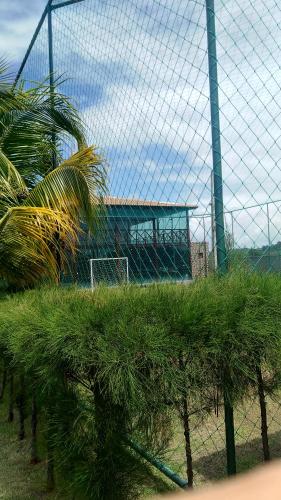 a fence with palm trees in front of a soccer field at Condomínio Village 4 Carneiros casa 40 in Tamandaré