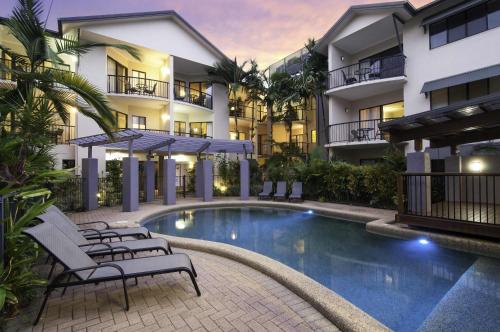 a hotel with a swimming pool in front of a building at Bay Villas Resort in Port Douglas