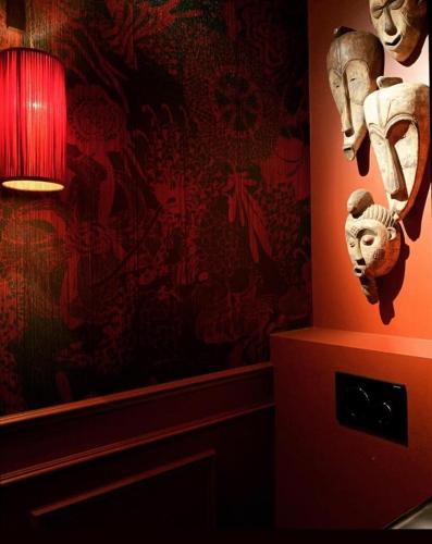 a room with a red wall with a mask and a lamp at Maison Fred Luxury Suites in Bruges