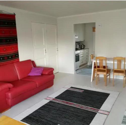 a living room with a red couch and a kitchen at Pajala, talo aavan reunalla in Nivala