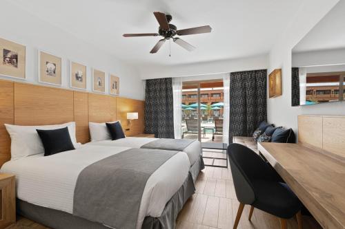 a hotel room with a large bed and a desk at Hotel Riu Tikida Garden - Adults Only - All Inclusive in Marrakech