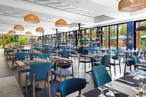a restaurant with tables and chairs and windows at Hotel Riu Tikida Garden - Adults Only - All Inclusive in Marrakech