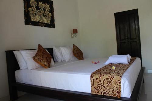 1 cama con sábanas blancas y almohadas en una habitación en Magus Homestay, en Pemuteran