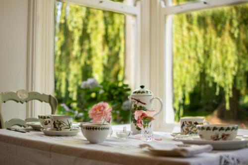 een tafel met theekopjes en een vaas erop bij Tudhoe Park House in Durham
