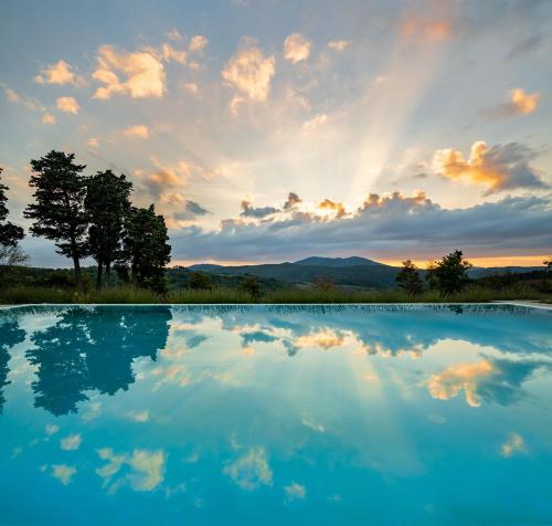 uma piscina de água com um pôr-do-sol ao fundo em Florence Country Residence em Vaglia